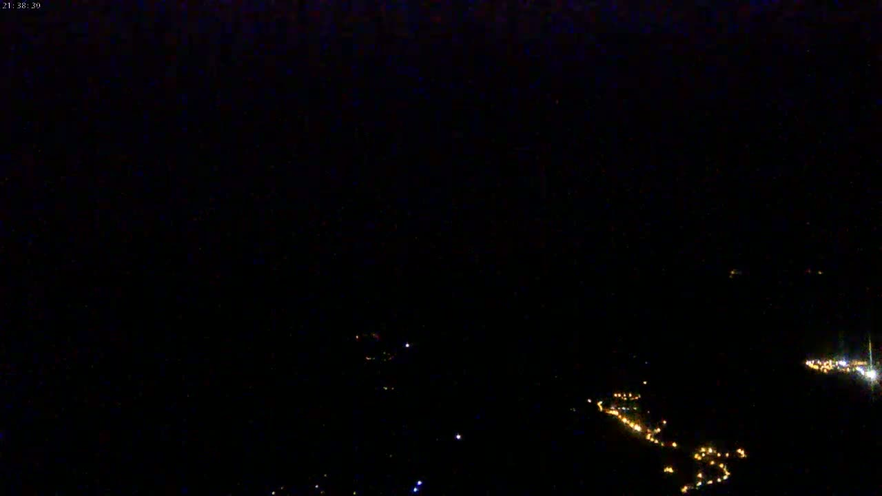 A nighttime, high-angle view shows scattered, faint lights below against an almost entirely dark sky.