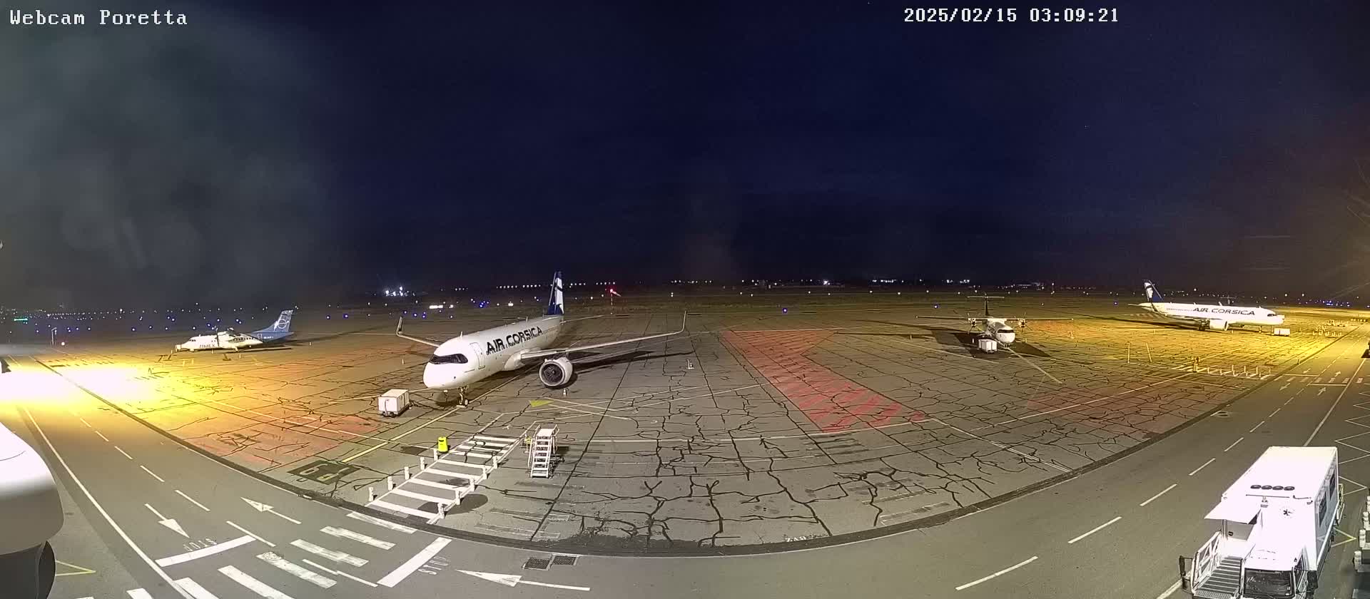 At night, several airplanes are parked on a tarmac under a dark, mostly clear sky.