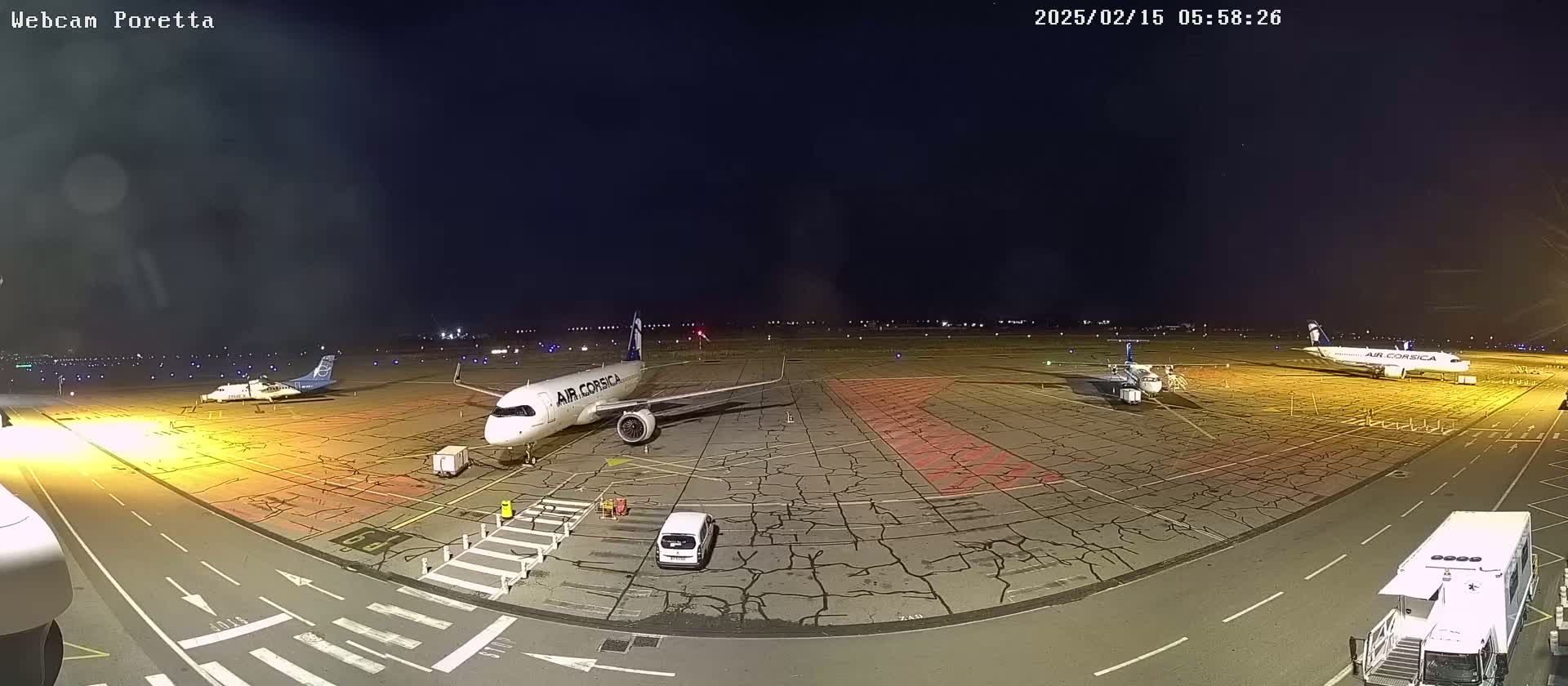 At night, several airplanes are parked on a tarmac with cracked pavement under a dark sky.