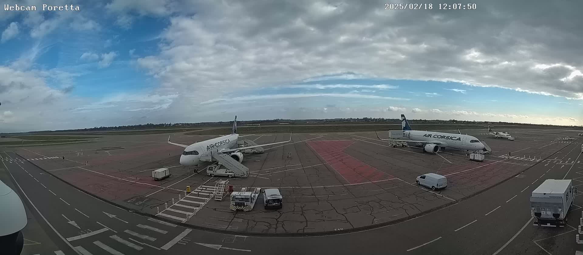 Two Air Corsica airplanes are parked on an airport tarmac under a partly cloudy sky.