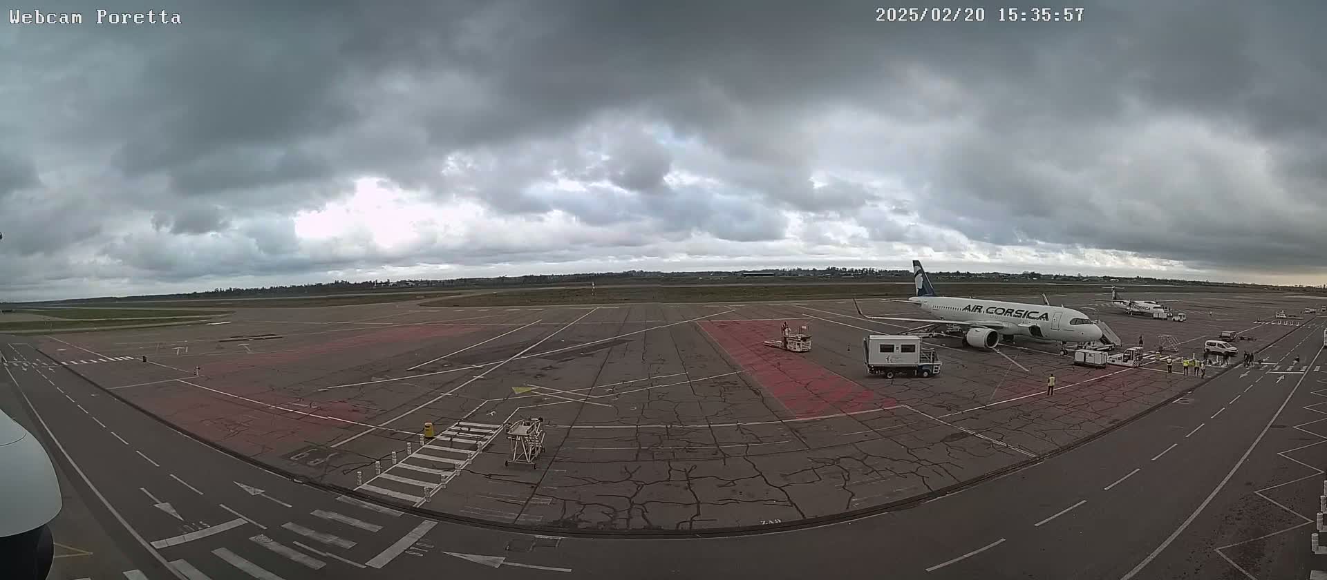 An airplane is parked on an airport tarmac under an overcast sky.