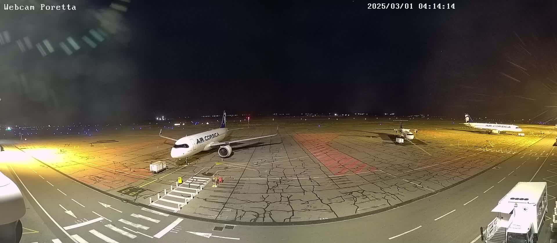 At night, two airplanes sit on a tarmac with cracked pavement under a clear, dark sky.