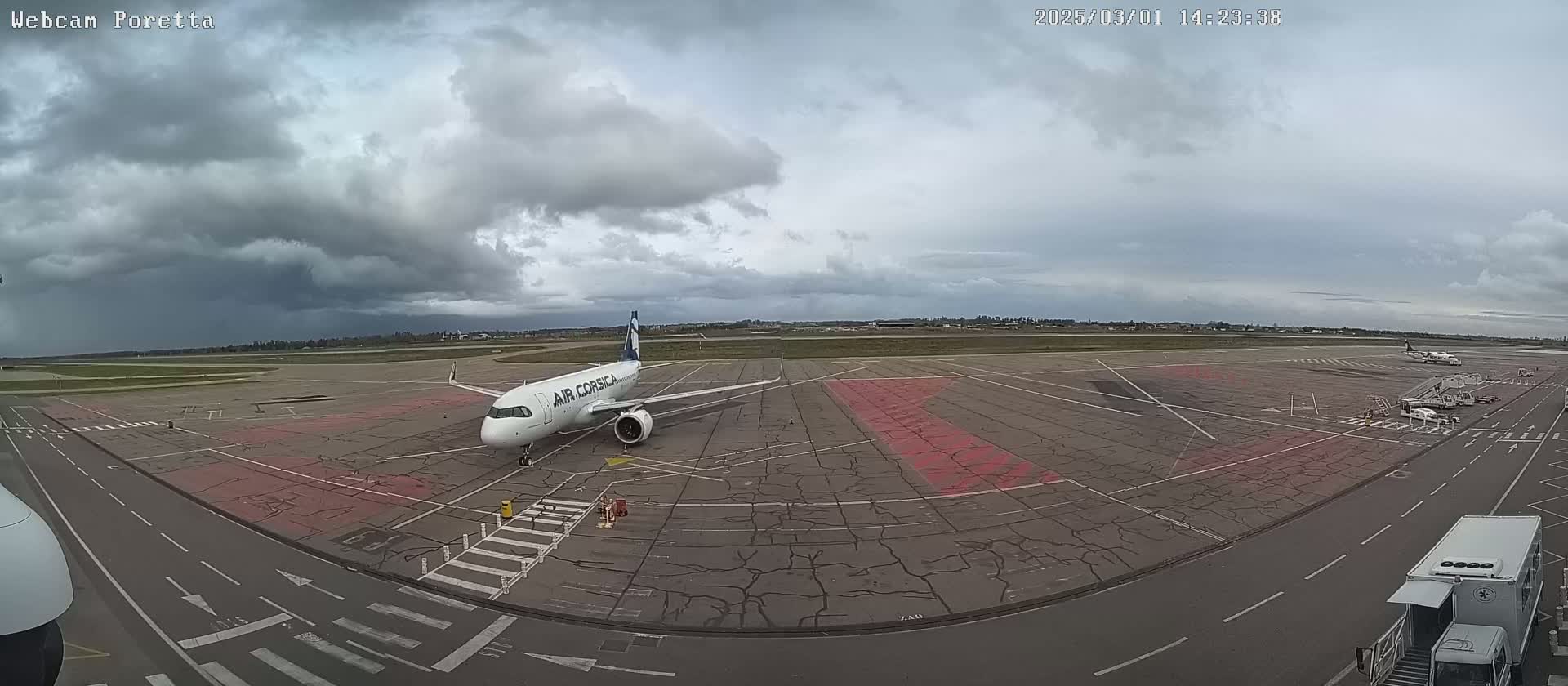 An Air Corsica airplane is parked on an airport tarmac under a cloudy sky.