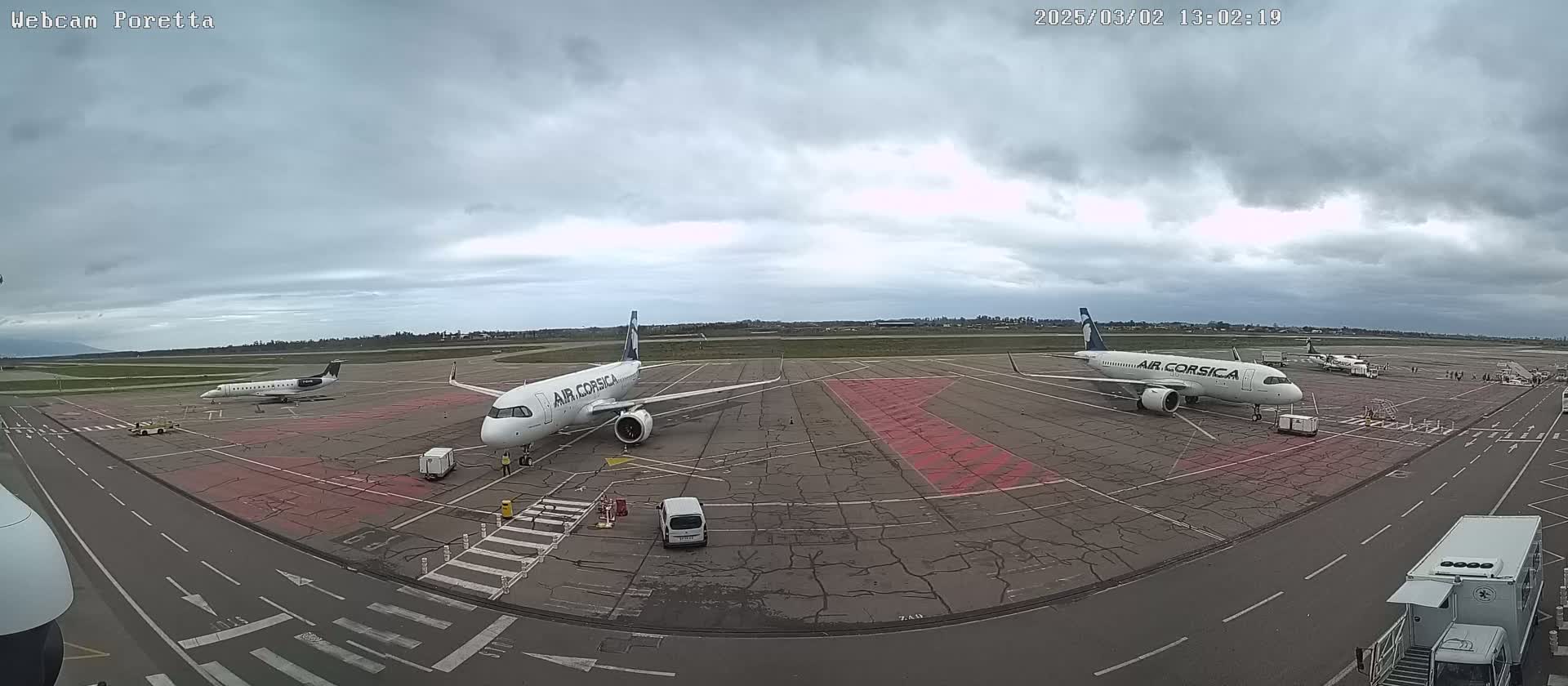 Several airplanes are parked on a tarmac under an overcast sky.