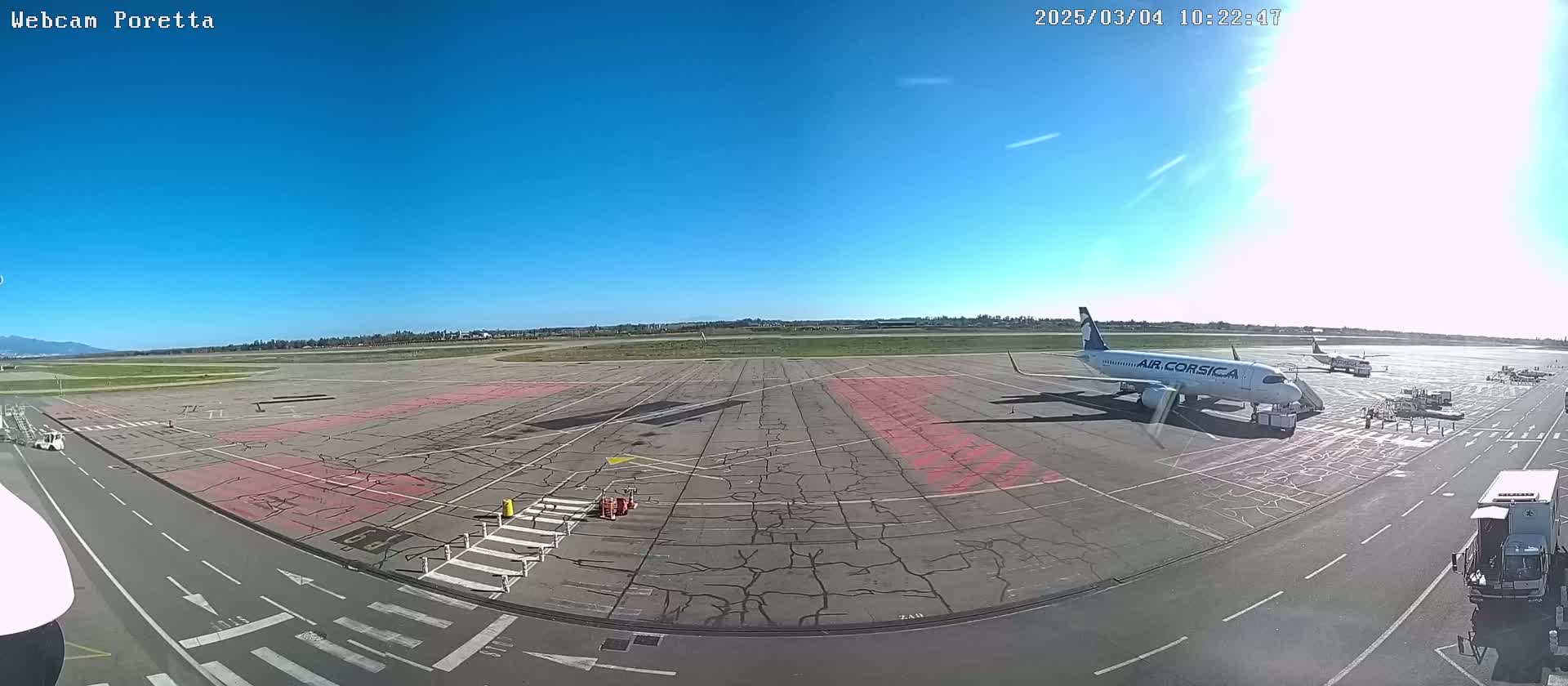 A passenger airplane is parked on a tarmac under a clear blue sky at an airport.