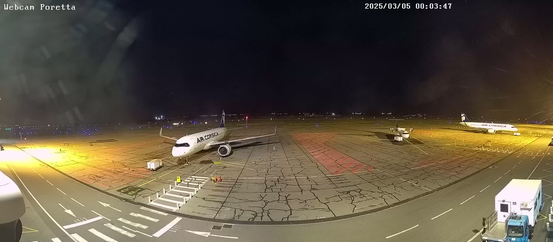 Two airplanes are parked on a tarmac at night under a clear, dark sky.