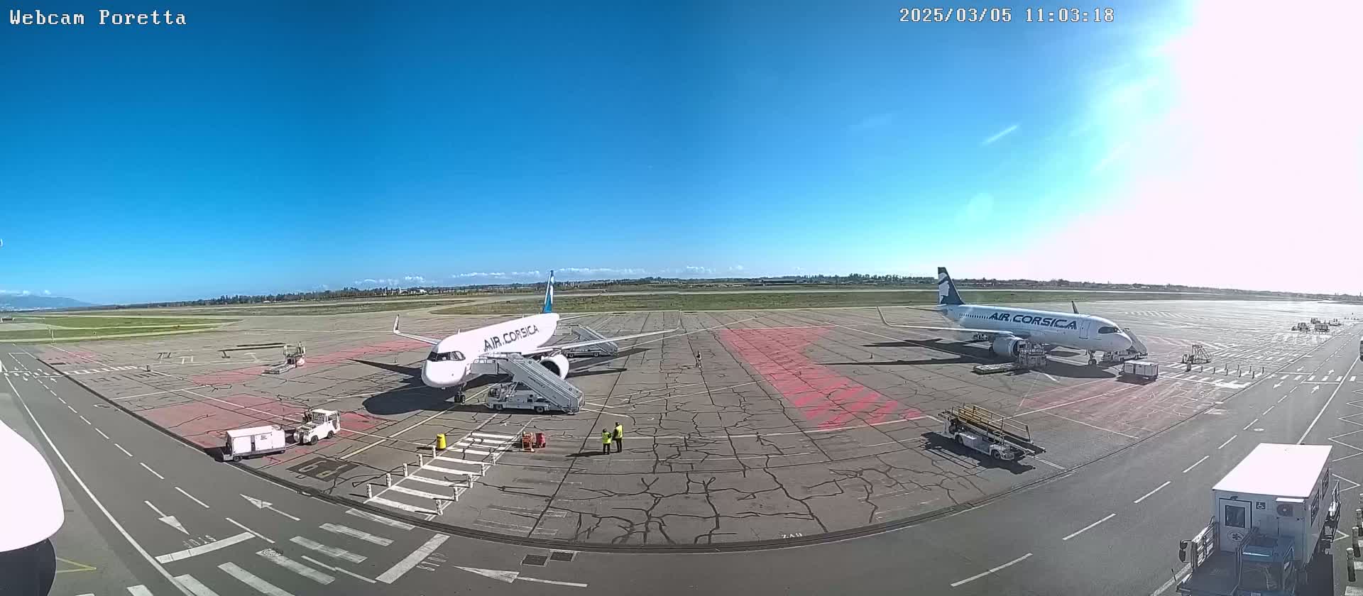 Two Air Corsica airplanes are parked on an airport tarmac under a clear, sunny sky.
