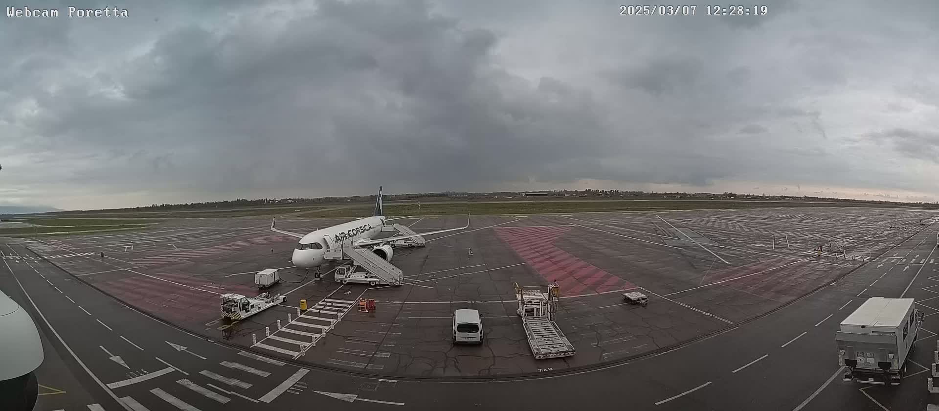 An Air Corsica airplane is parked at an airport tarmac under an overcast sky.