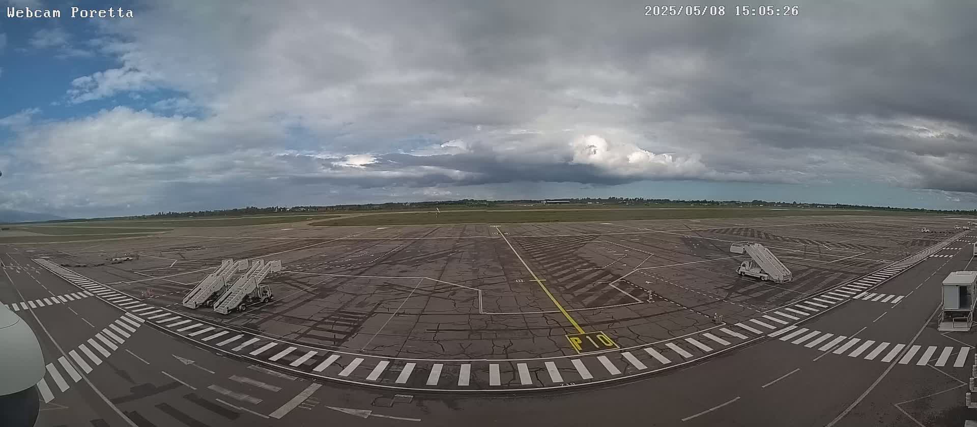 An airport tarmac with several jet bridges under a mostly cloudy sky.