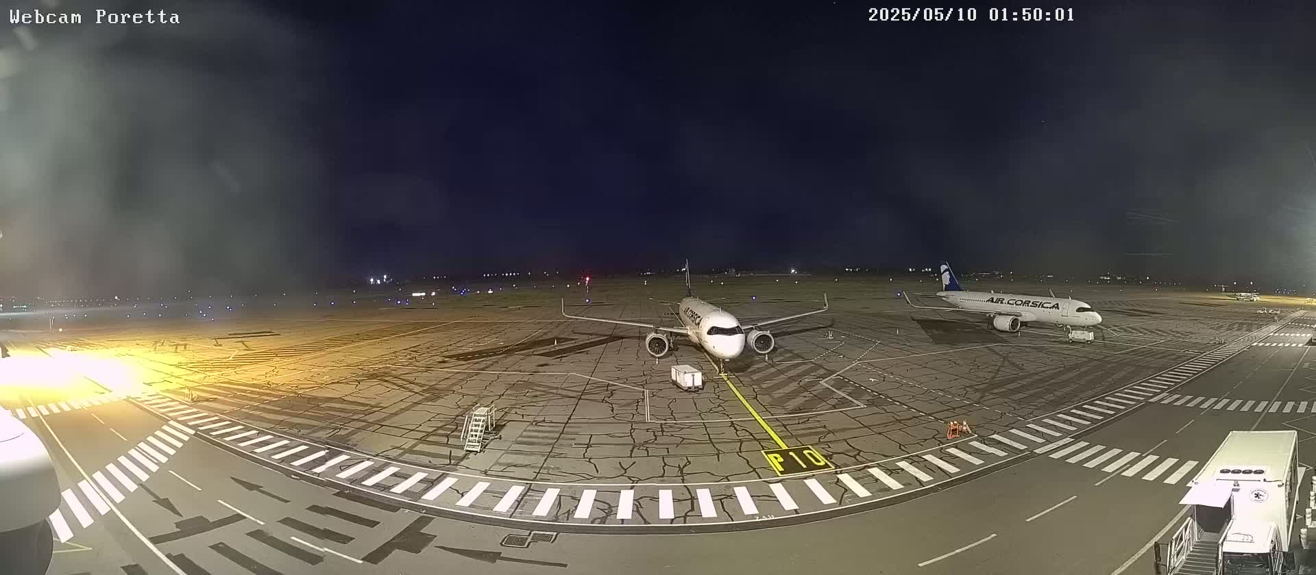 Two airplanes are parked on a tarmac at night under a dark sky.