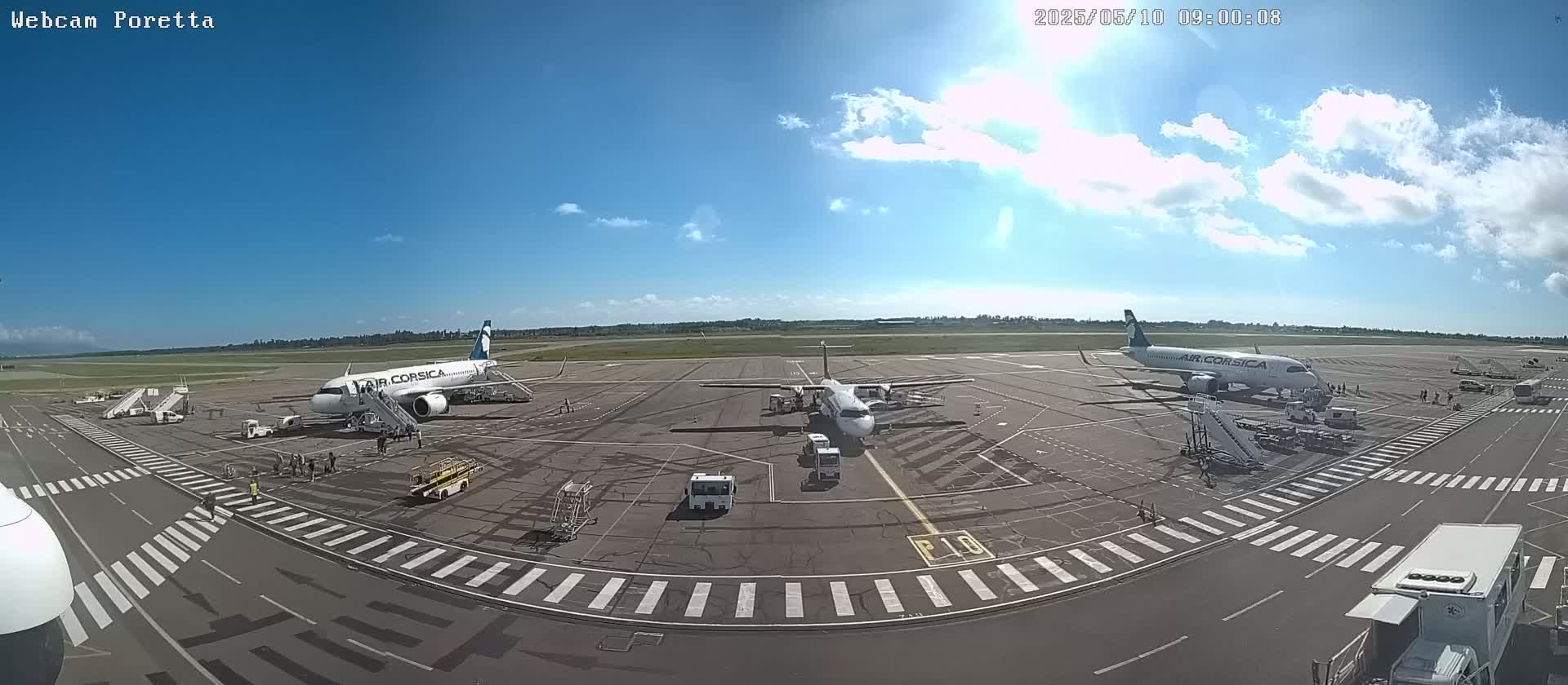 Three airplanes are parked on an airport tarmac under a mostly sunny sky with scattered clouds.