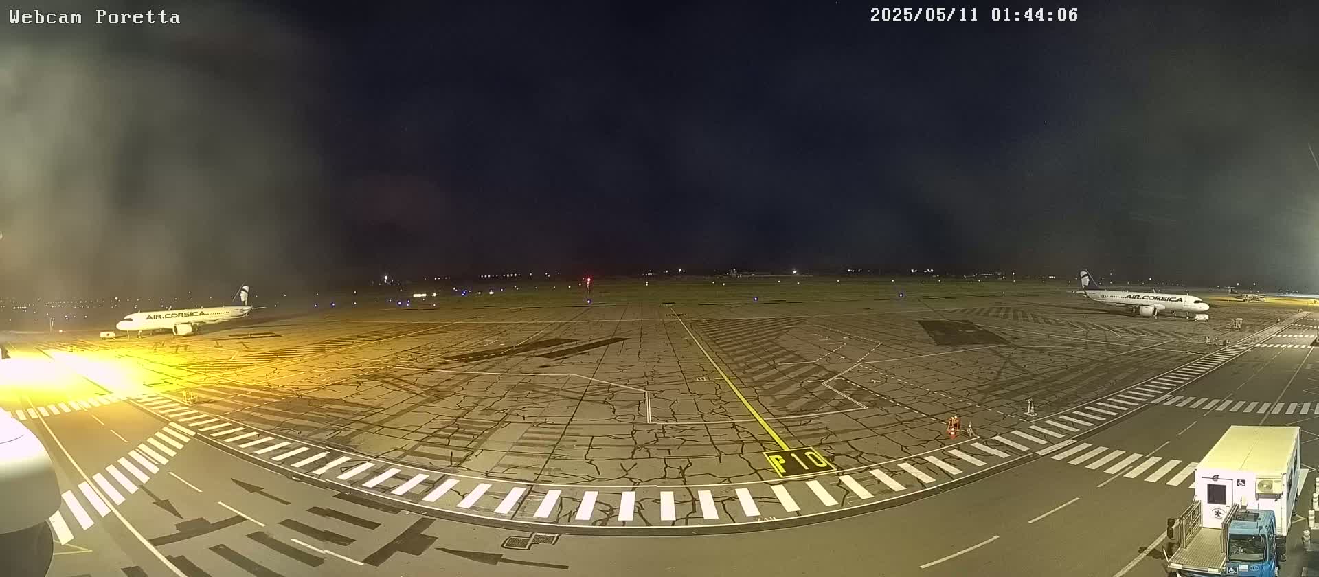 Two airplanes are parked on a tarmac at night, under a mostly clear sky.