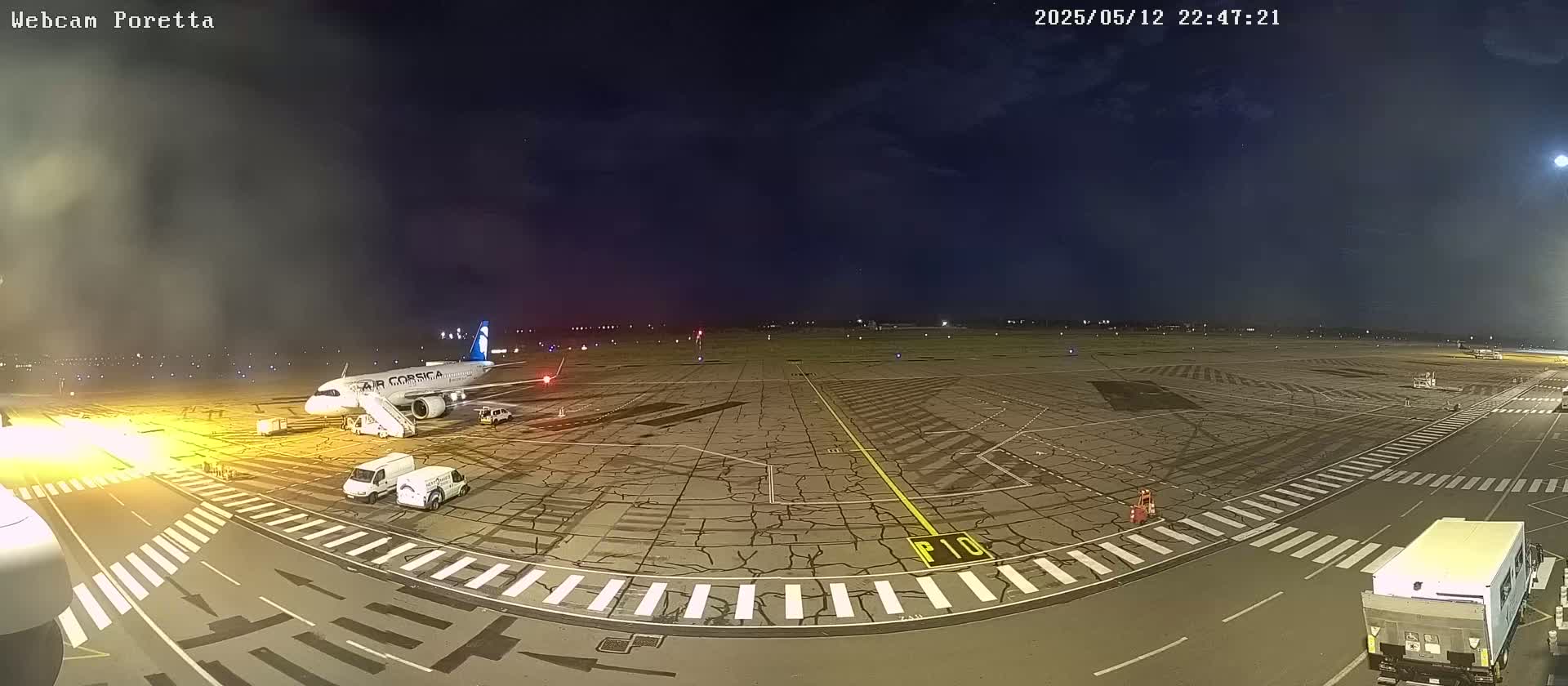 A passenger airplane is parked on an airport tarmac at night under a mostly clear sky.