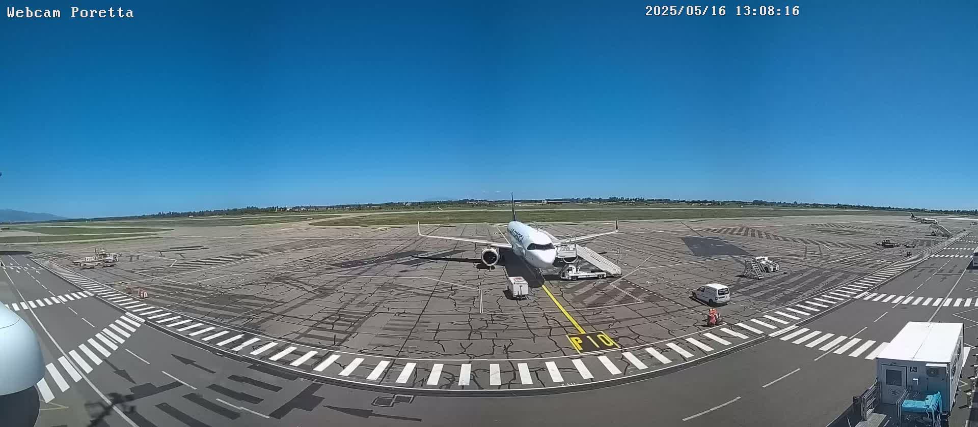 A passenger airplane is parked on an airport tarmac under a clear blue sky.