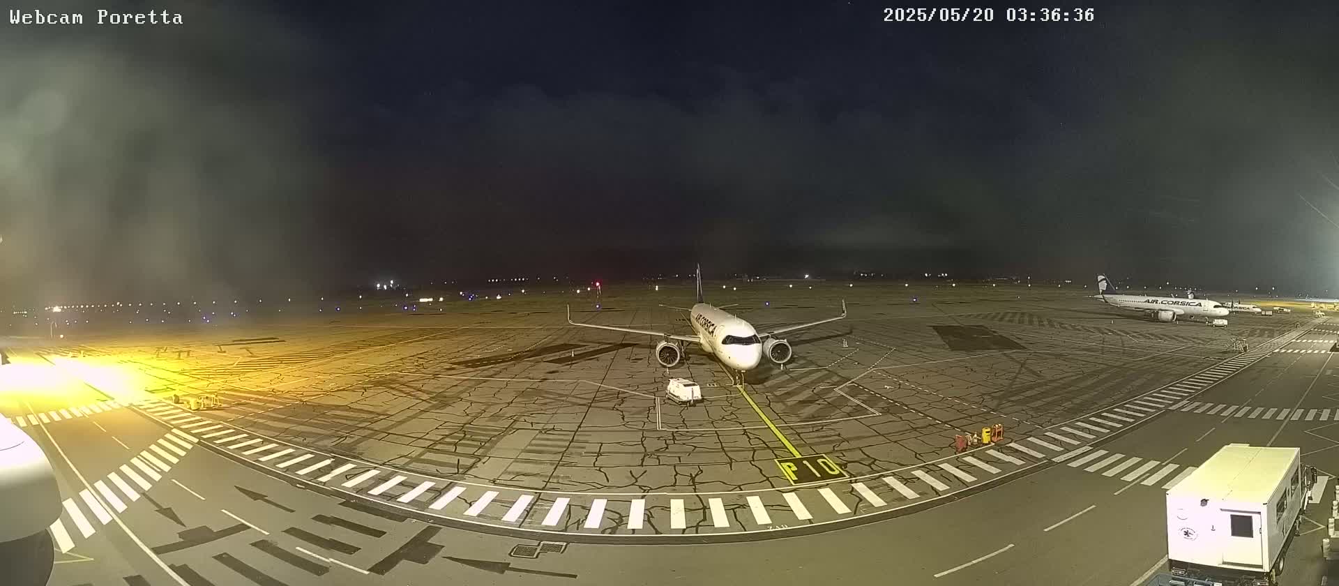 A passenger airplane is parked on an airport tarmac at night under a cloudy sky.