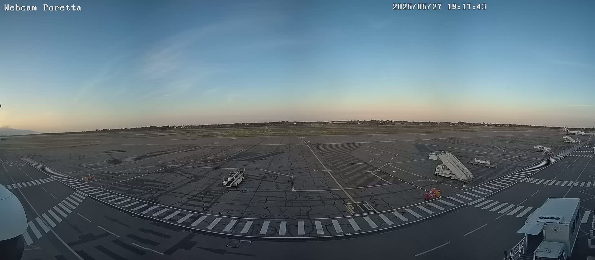 An airport tarmac at dusk, showing several aircraft and ground support equipment under a clear sky.