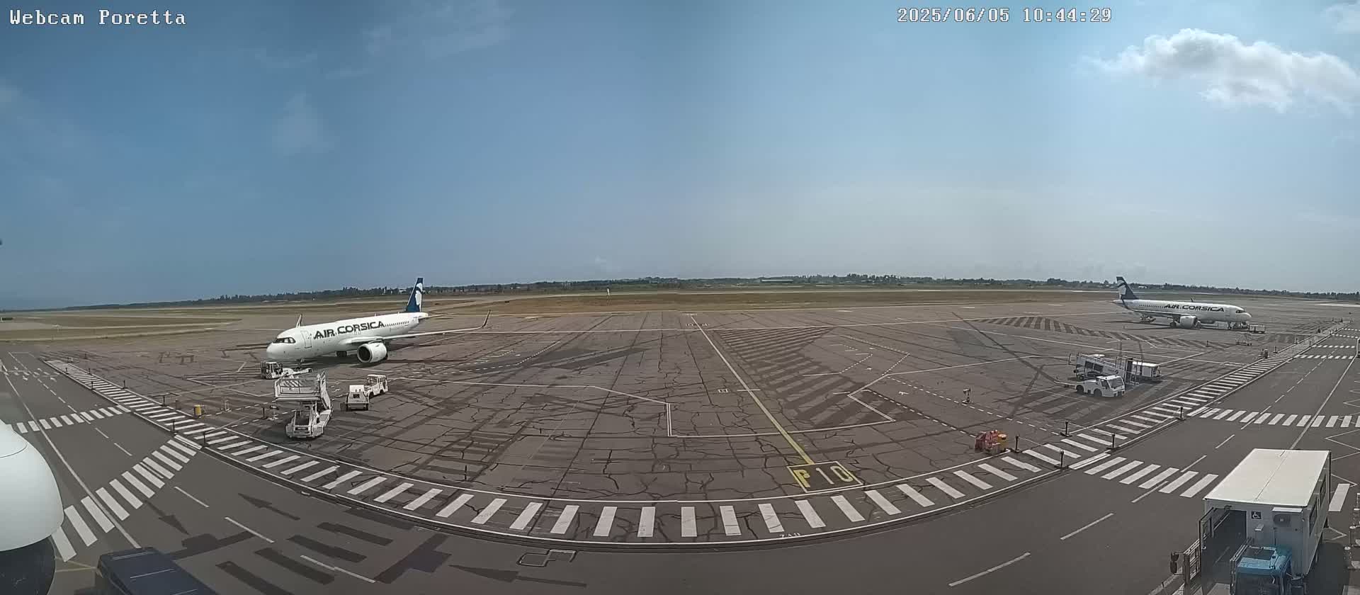 Two Air Corsica airplanes are parked on a tarmac on a partly cloudy day.