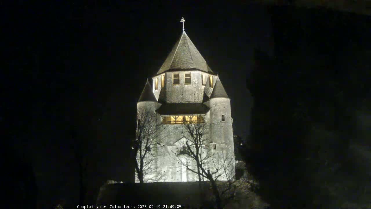 A stone tower, illuminated at night, stands silhouetted against a dark sky.