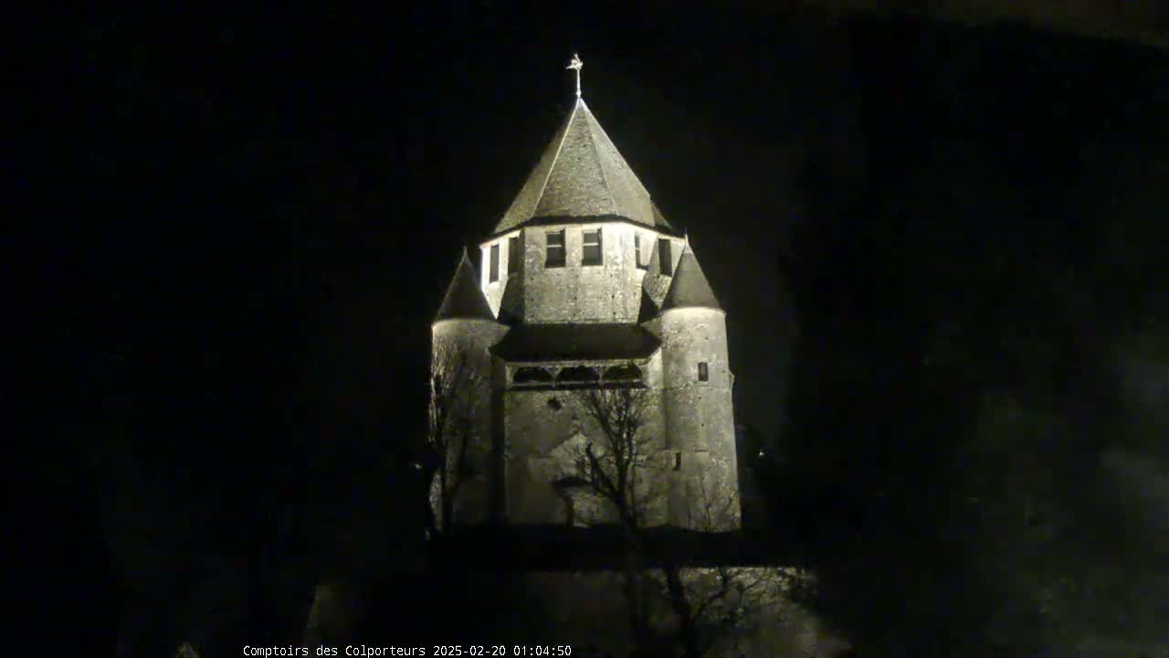A stone tower, illuminated at night, stands against a dark sky.