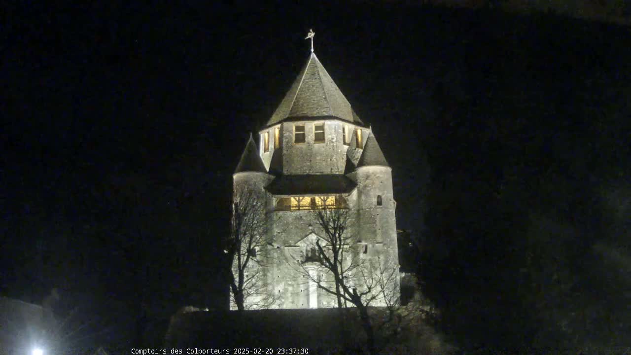 A stone tower, illuminated at night, stands silhouetted against a dark sky.