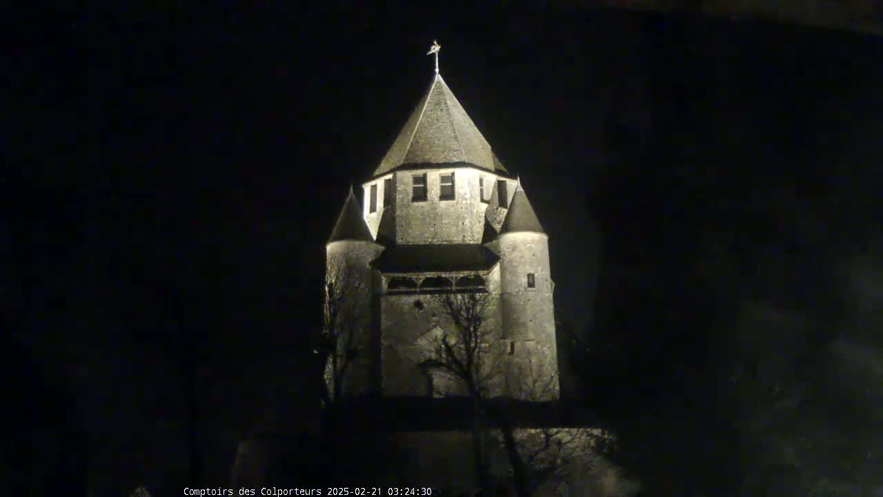 A stone tower, illuminated at night, stands against a dark sky.