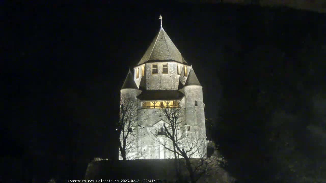 A tall, stone tower, illuminated at night, stands against a dark sky.