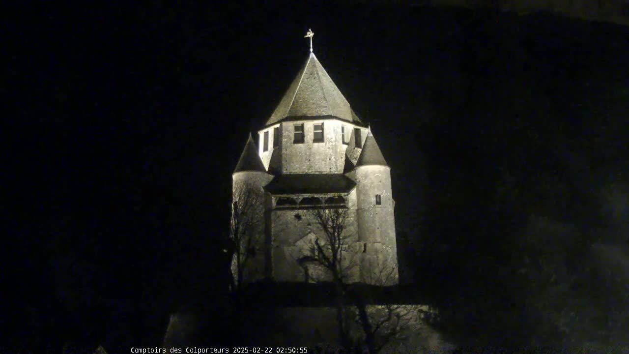 A stone tower, illuminated at night, stands against a dark sky.