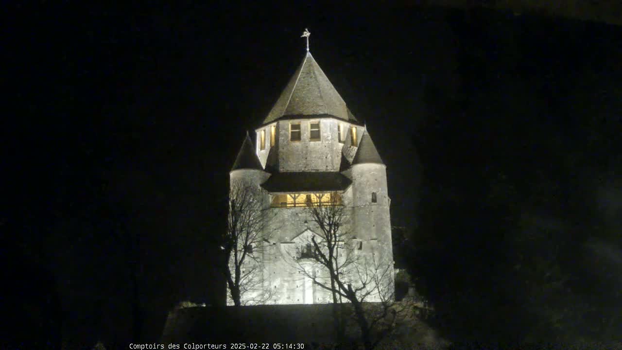 A stone tower, illuminated at night, stands silhouetted against a dark sky.