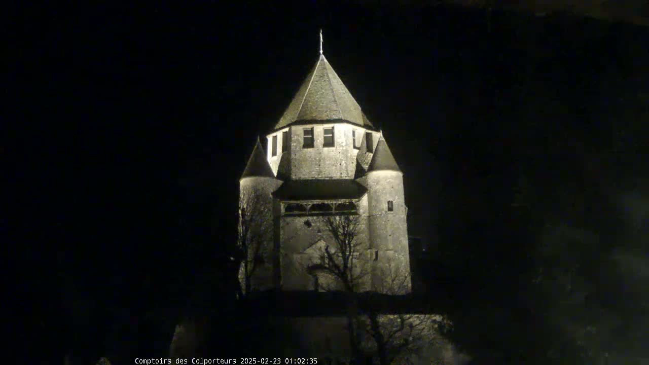 A stone tower, illuminated at night, stands against a dark sky.