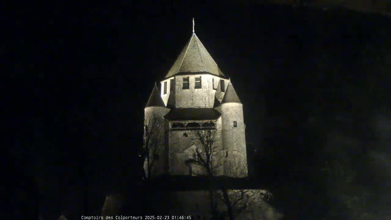 A stone tower, illuminated at night, stands against a dark sky.