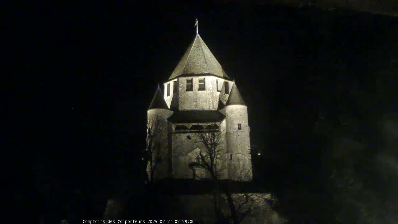 A stone tower, illuminated at night, stands against a dark sky.