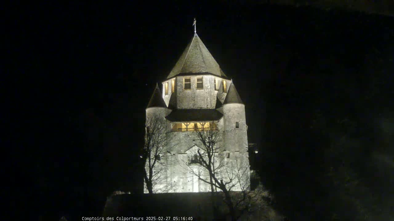 A stone tower, illuminated at night, stands against a dark, clear sky.
