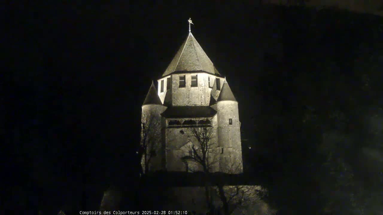 A stone tower, illuminated at night, stands against a dark sky.