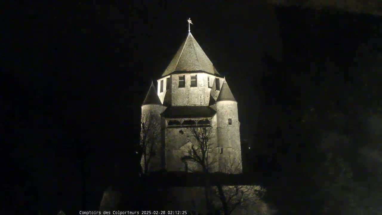 A stone tower, illuminated at night, stands against a dark sky.