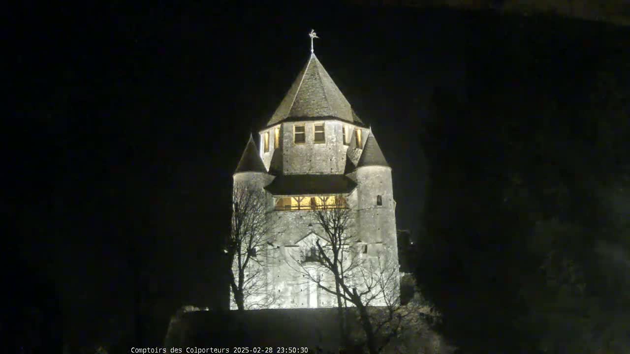 A stone tower, illuminated at night, stands silhouetted against a dark sky.