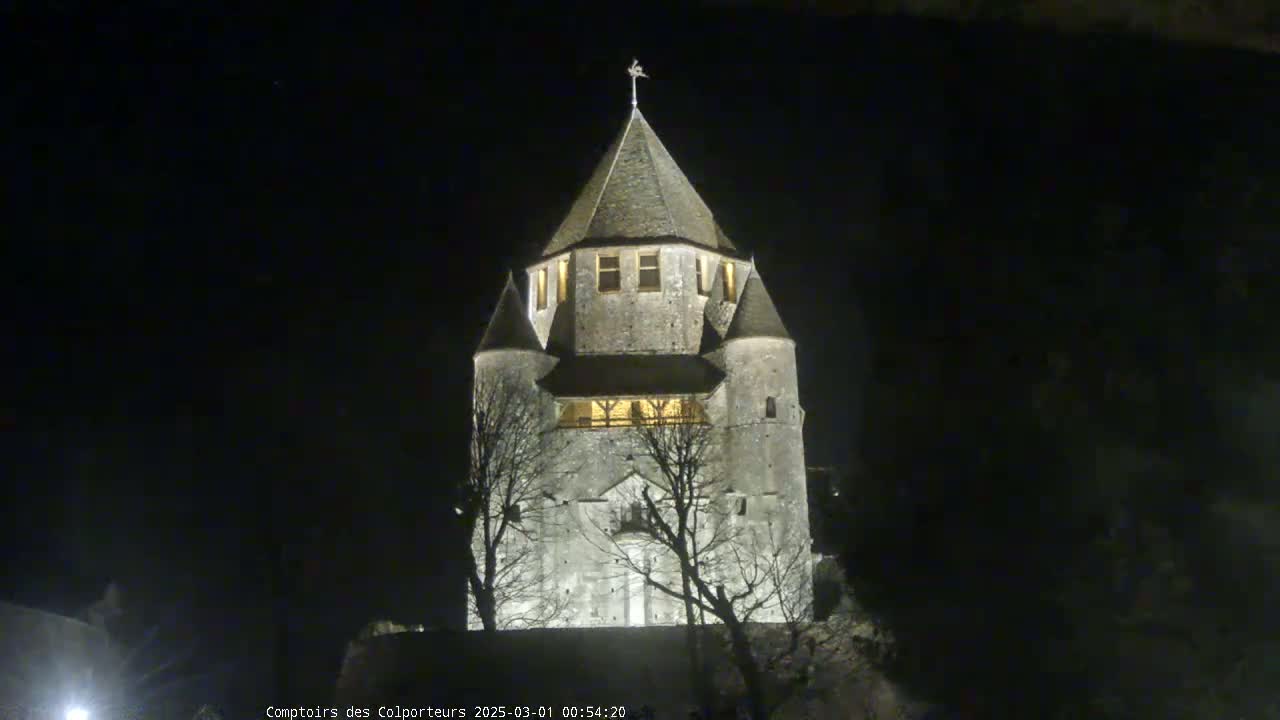 A stone tower, illuminated at night, stands silhouetted against a dark sky.