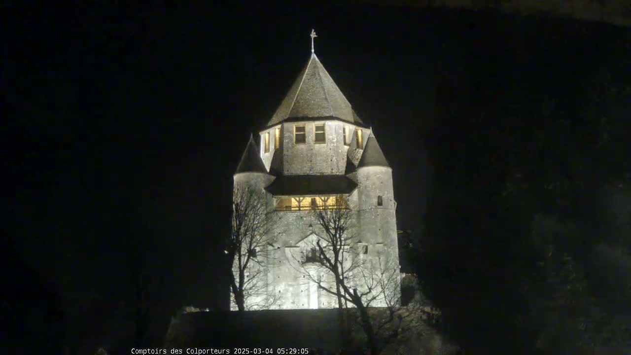 A stone tower, illuminated at night, stands silhouetted against a dark sky.