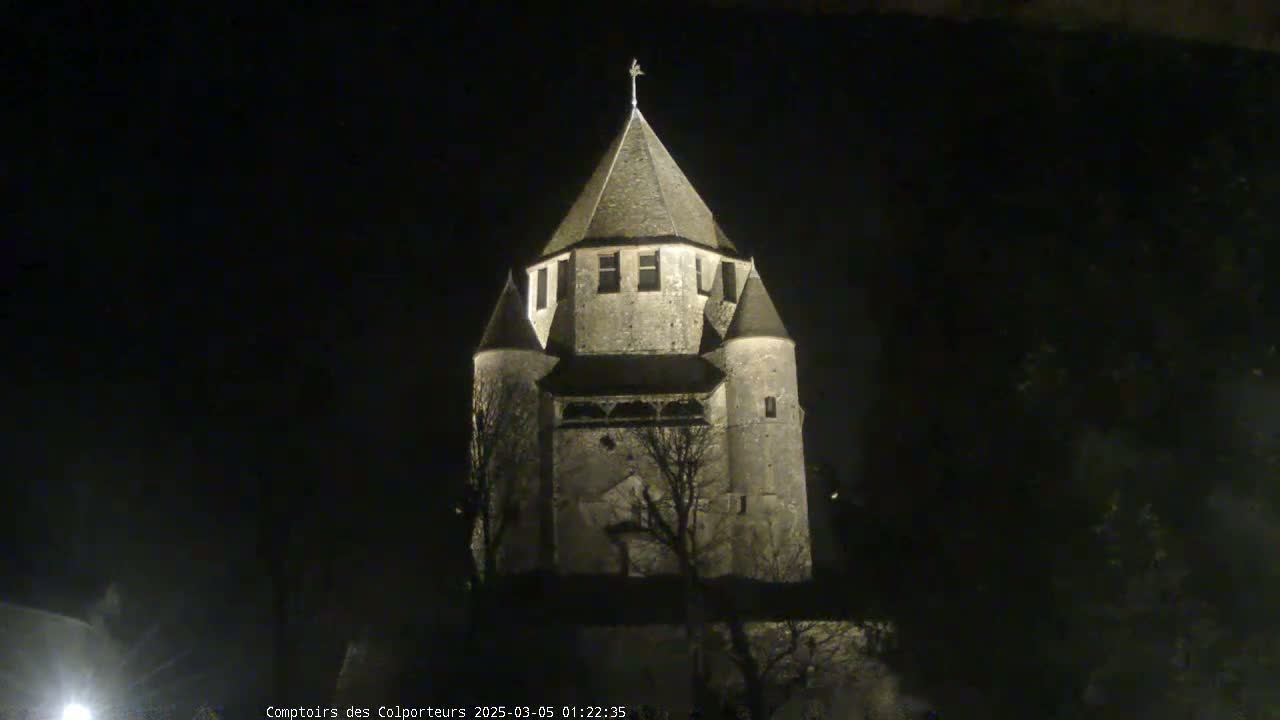A stone tower, illuminated at night, stands against a dark sky.