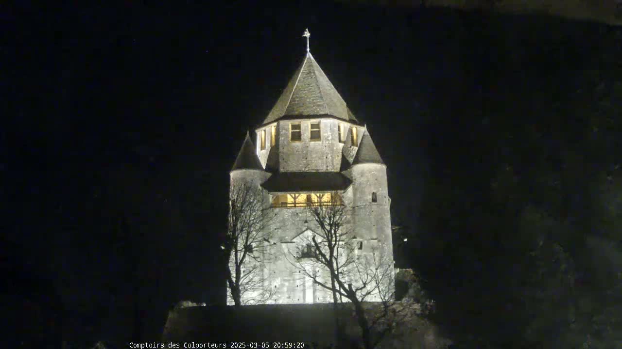 A stone tower, illuminated at night, stands under a dark, clear sky.