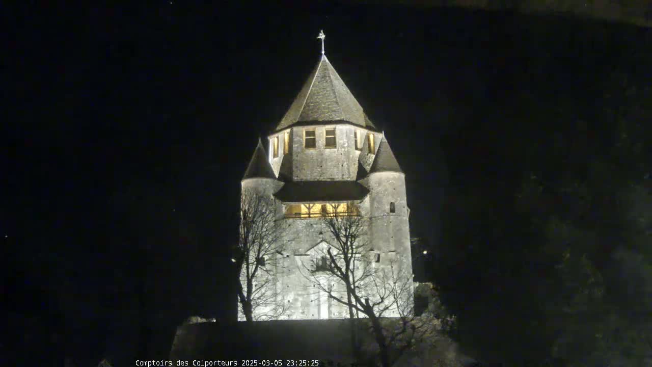 A stone tower, illuminated at night, stands against a dark sky.