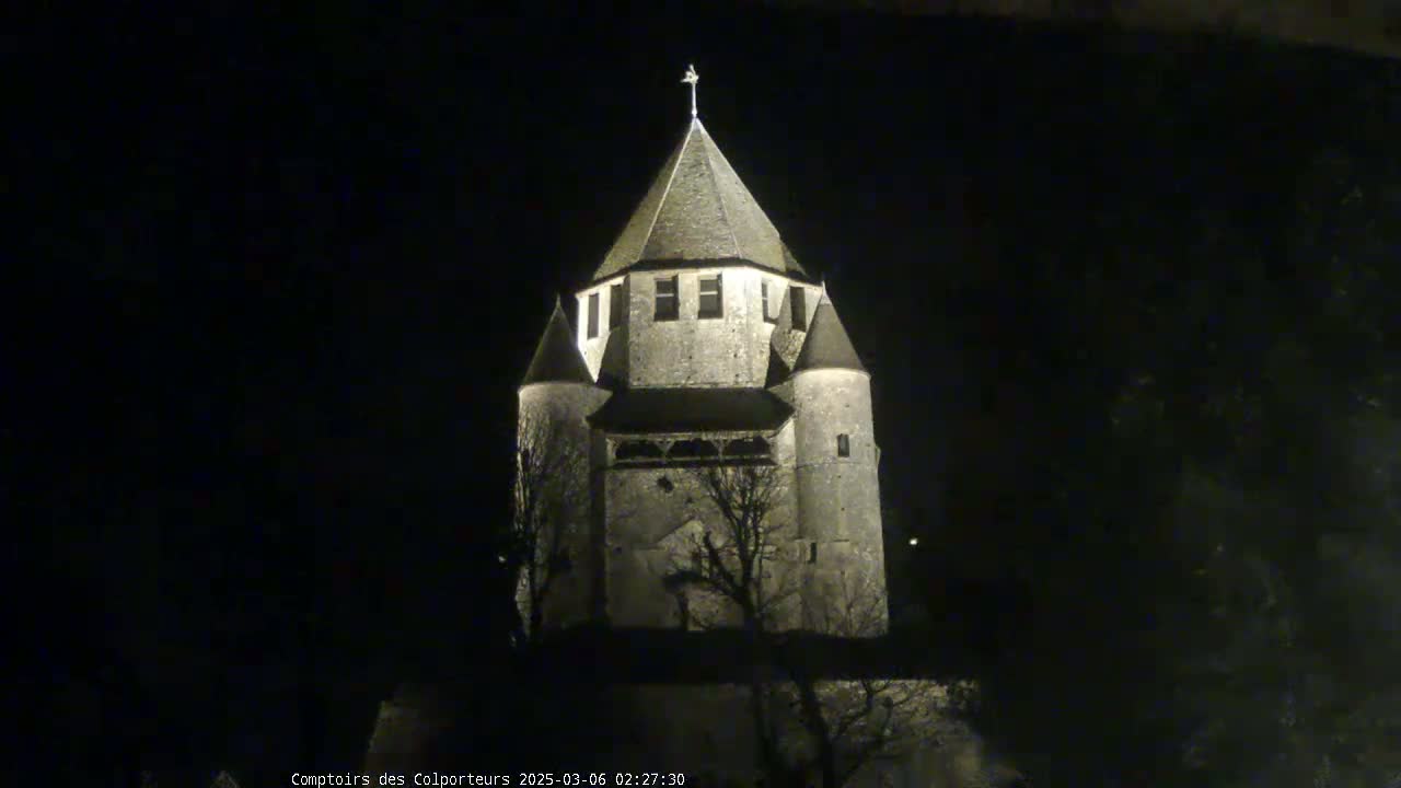A stone tower, illuminated at night, stands against a dark sky.