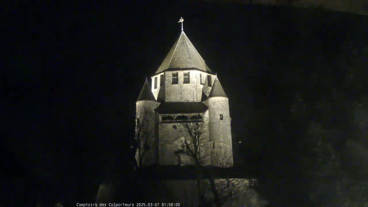 A stone tower, illuminated at night, stands against a dark sky.