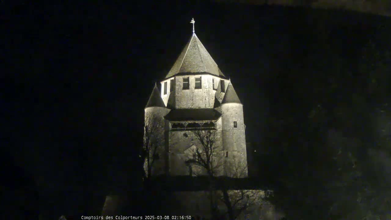A stone tower, illuminated at night, stands against a dark sky.
