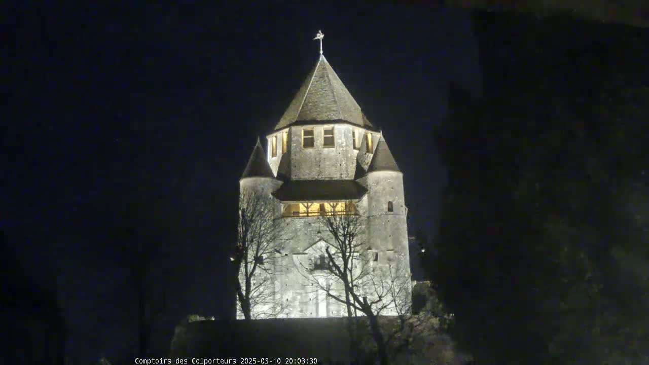A stone tower, illuminated at night, stands against a dark, clear sky.