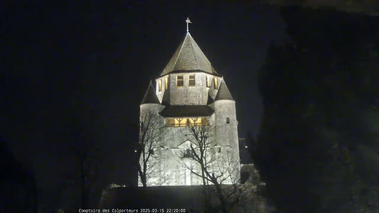 A stone tower, illuminated at night, stands silhouetted against a dark sky.