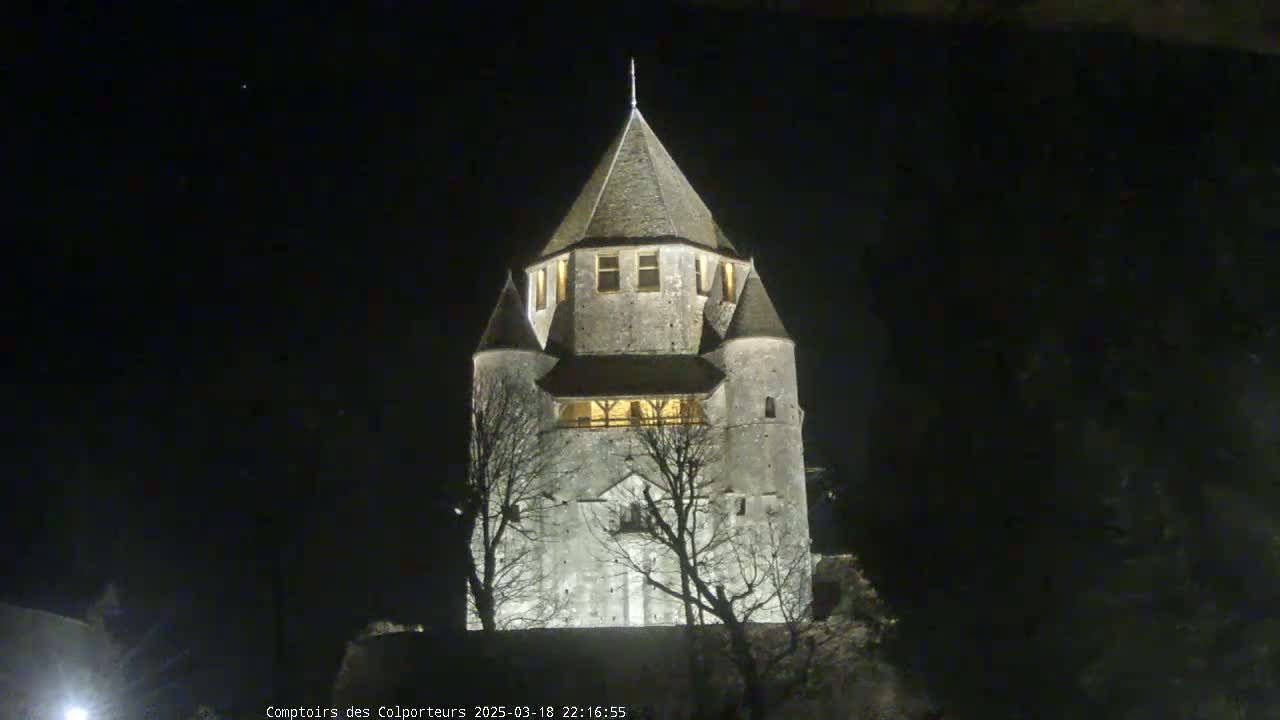 A tall, stone tower, illuminated at night, stands silhouetted against a dark, clear sky.