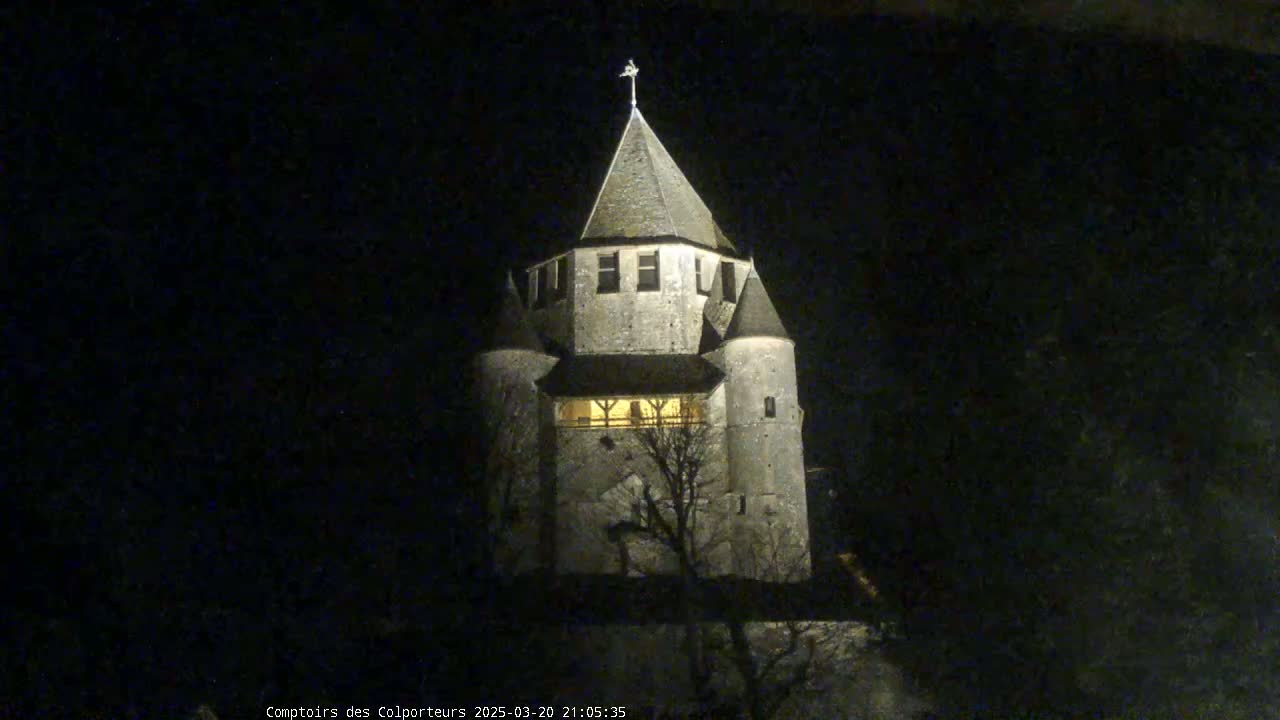 A stone tower, illuminated at night, stands against a dark, possibly snowy, sky.