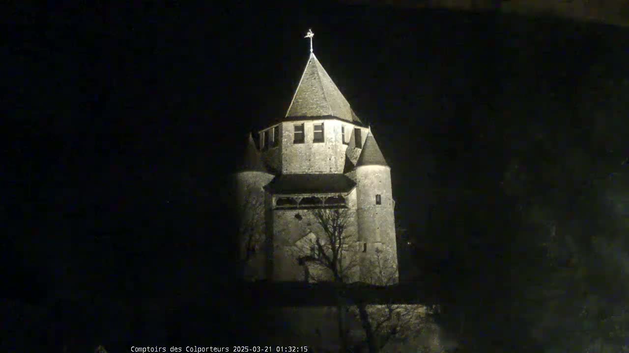 A stone tower, illuminated at night, stands silhouetted against a dark sky.