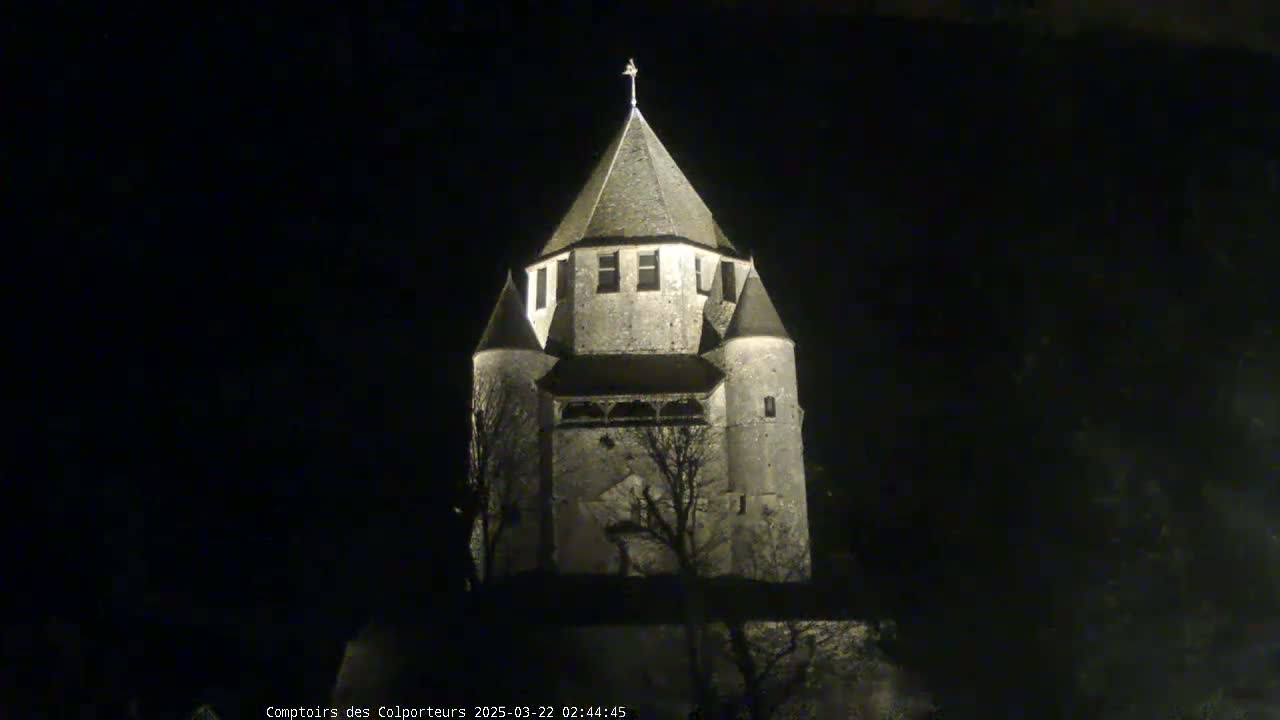 A stone tower, illuminated at night, stands against a dark sky.