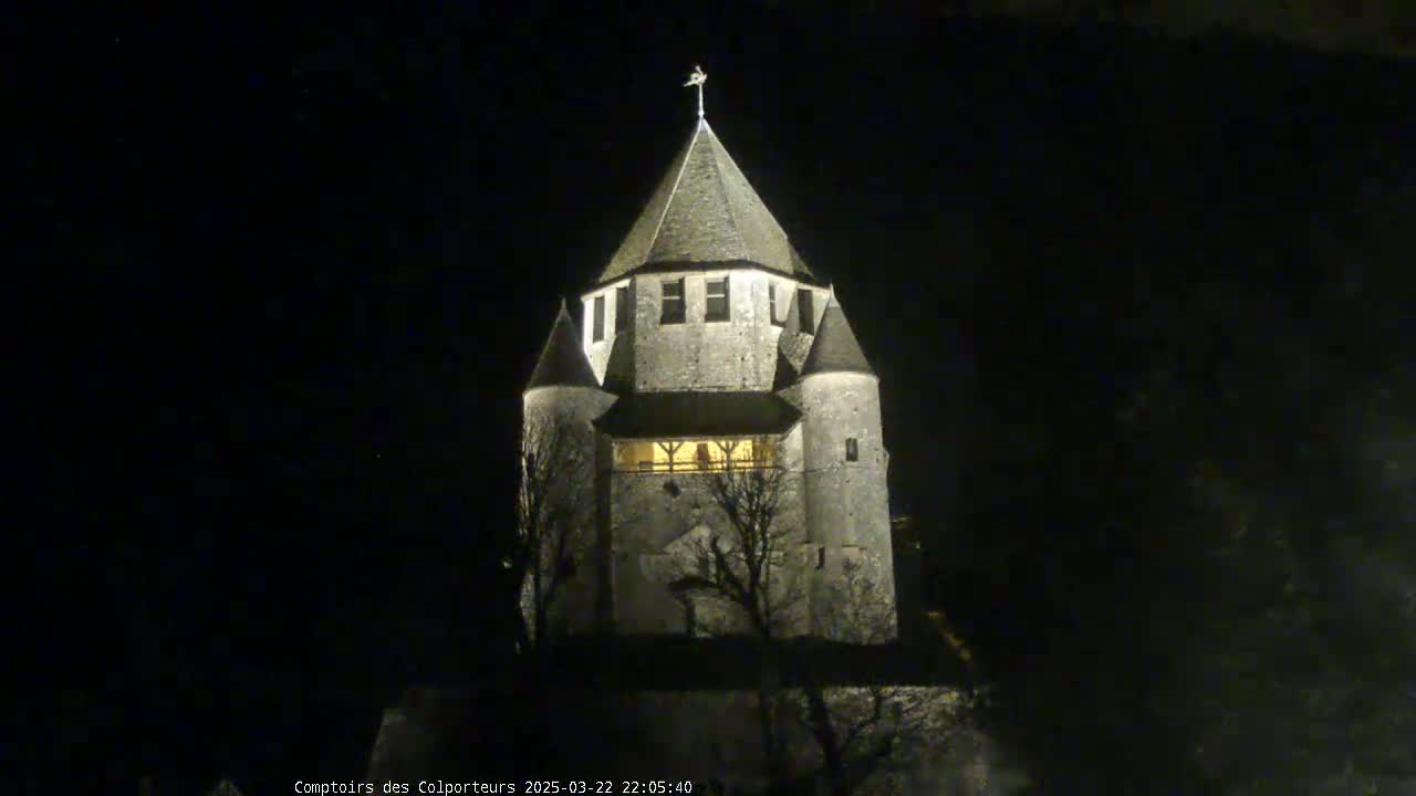 A stone tower, illuminated at night, stands against a dark sky.